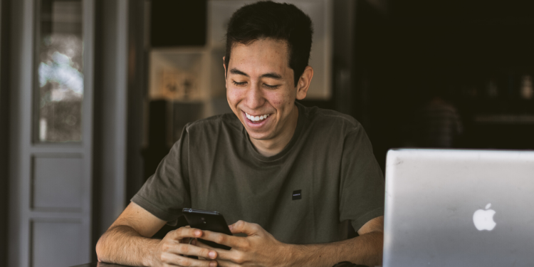 hombre feliz usando nido de teléfono móvil para computadora portátil