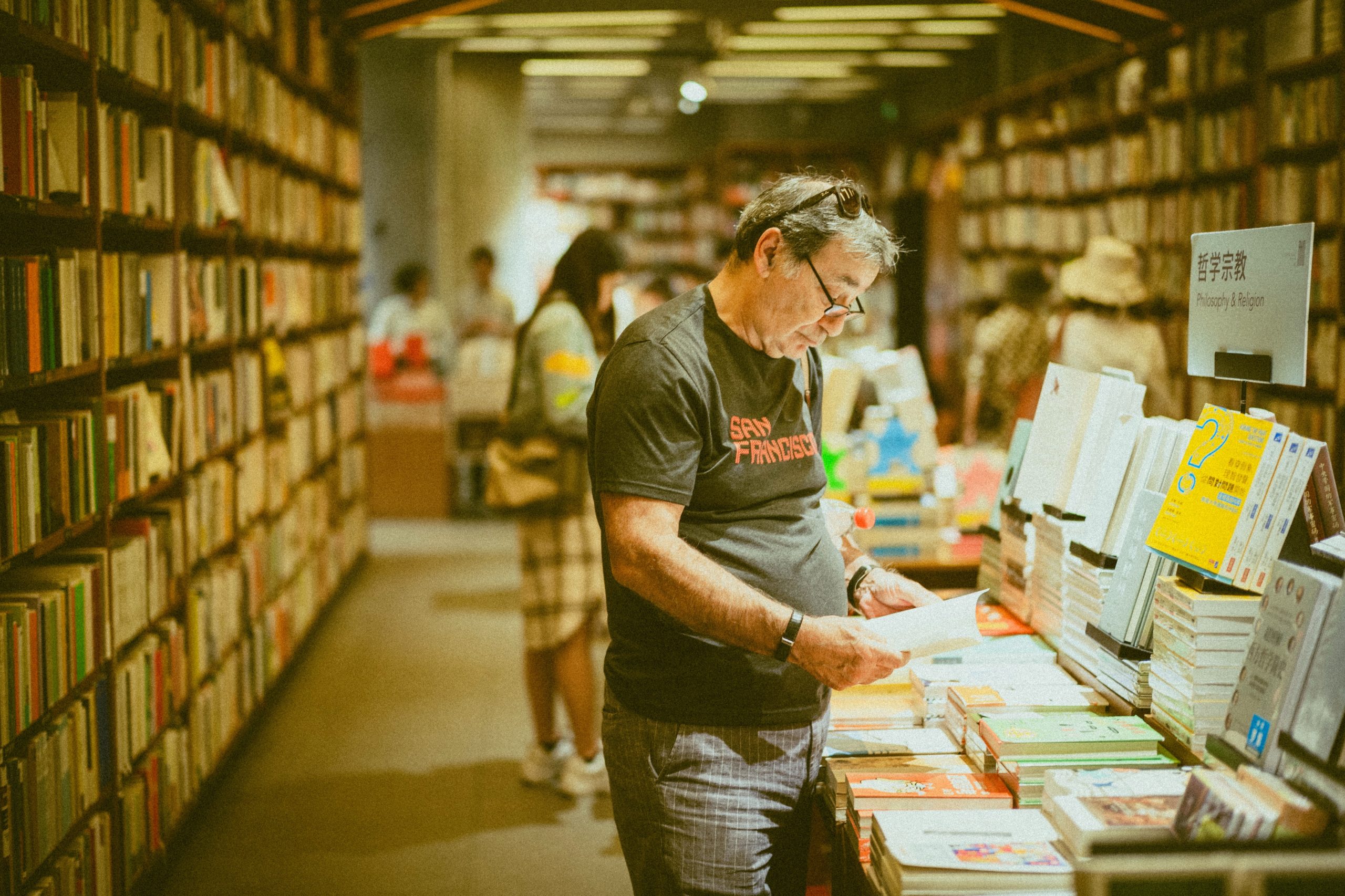 Un profesional independiente que realiza la curación de artículos para una tienda de Amazon mirando libros de una librería de segunda mano.