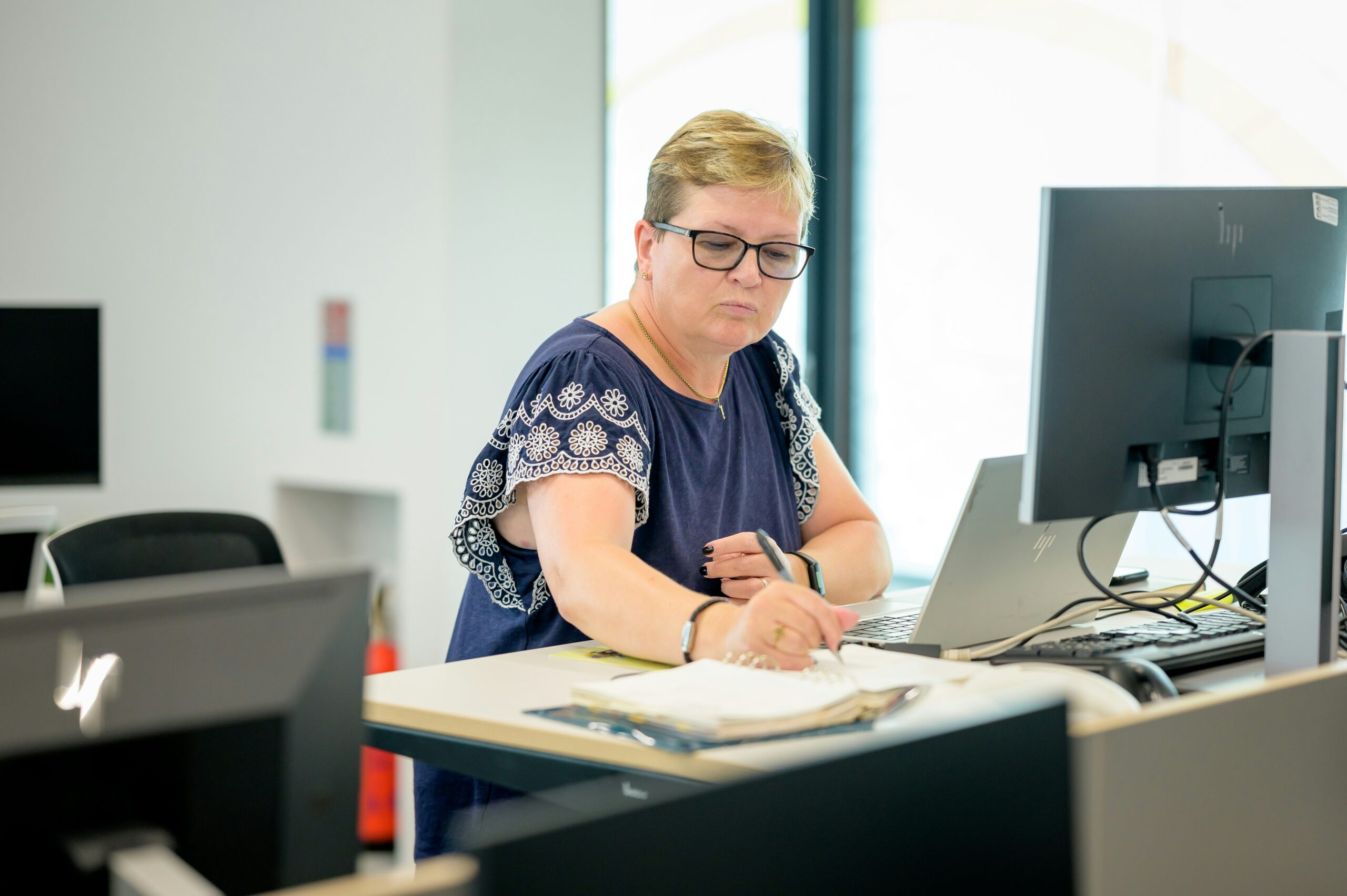 freelance bookkeeper at computer writing in a notebook