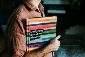 Person holding a book called Designing Brand Identity